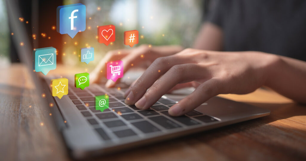 social icon float over a laptop as a woman types illustrating the concept of Social Media Marketing in 2023