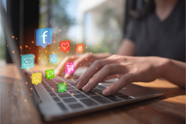 social icon float over a laptop as a woman types illustrating the concept of Social Media Marketing in 2023