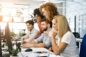 People gathered over a computer illustrating how IT and Marketing Companies can work together